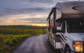 An rv driving down a country road at sunset.