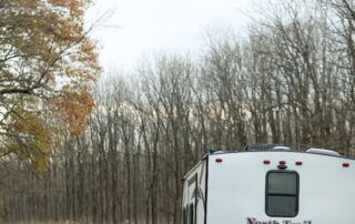 Two people standing next to an rv on a road.