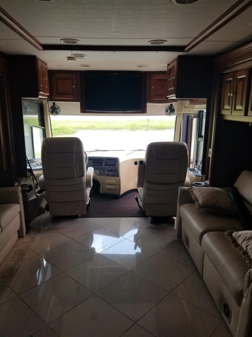 The interior of an rv with couches and a flat screen tv.