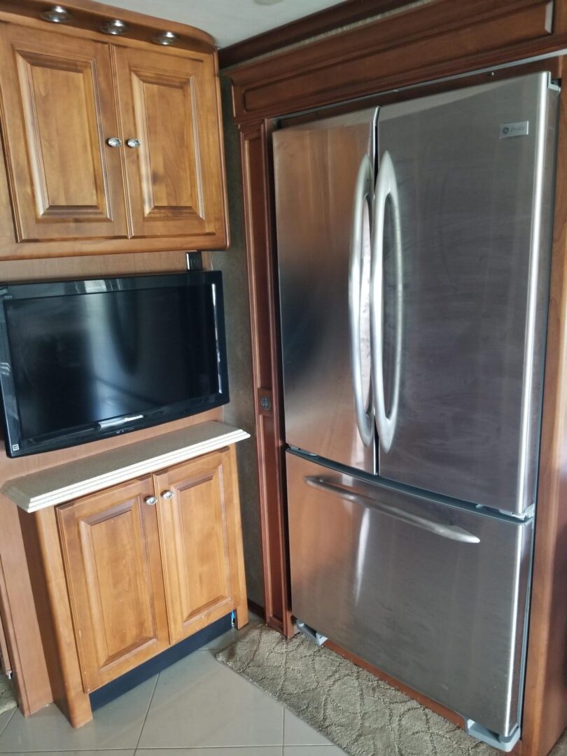 A stainless steel refrigerator and tv in a rv.