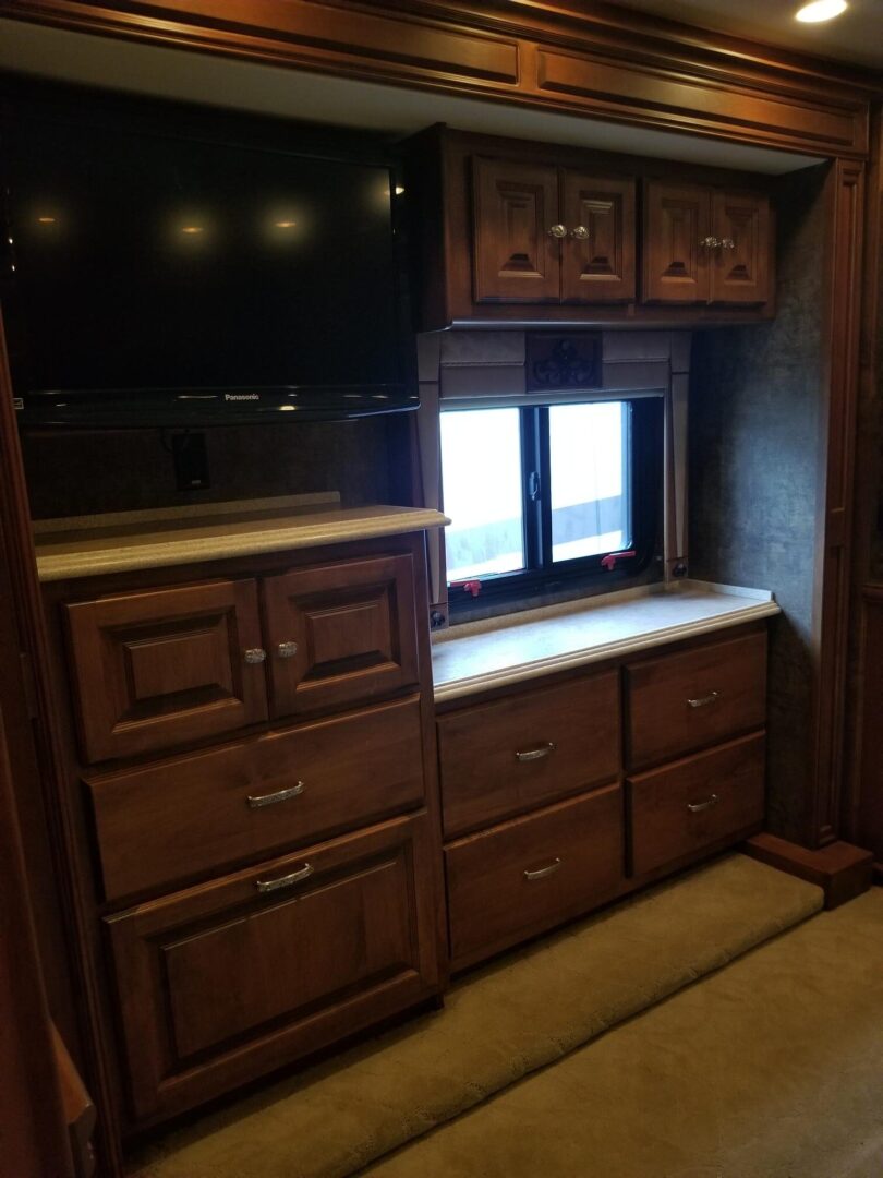 The interior of an rv with a tv and cabinets.
