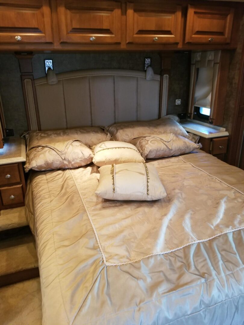 A bedroom in an rv with a bed and dresser.