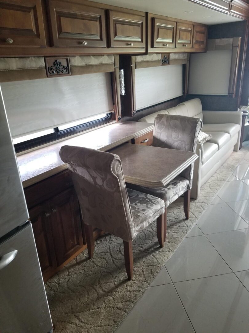An rv with a table and chairs and a refrigerator.