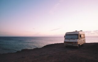 An rv parked on top of a cliff overlooking the ocean.