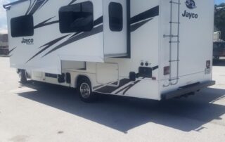 A white and black rv parked in a parking lot.