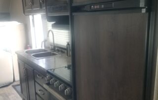 A kitchen in an rv with a stove and refrigerator.