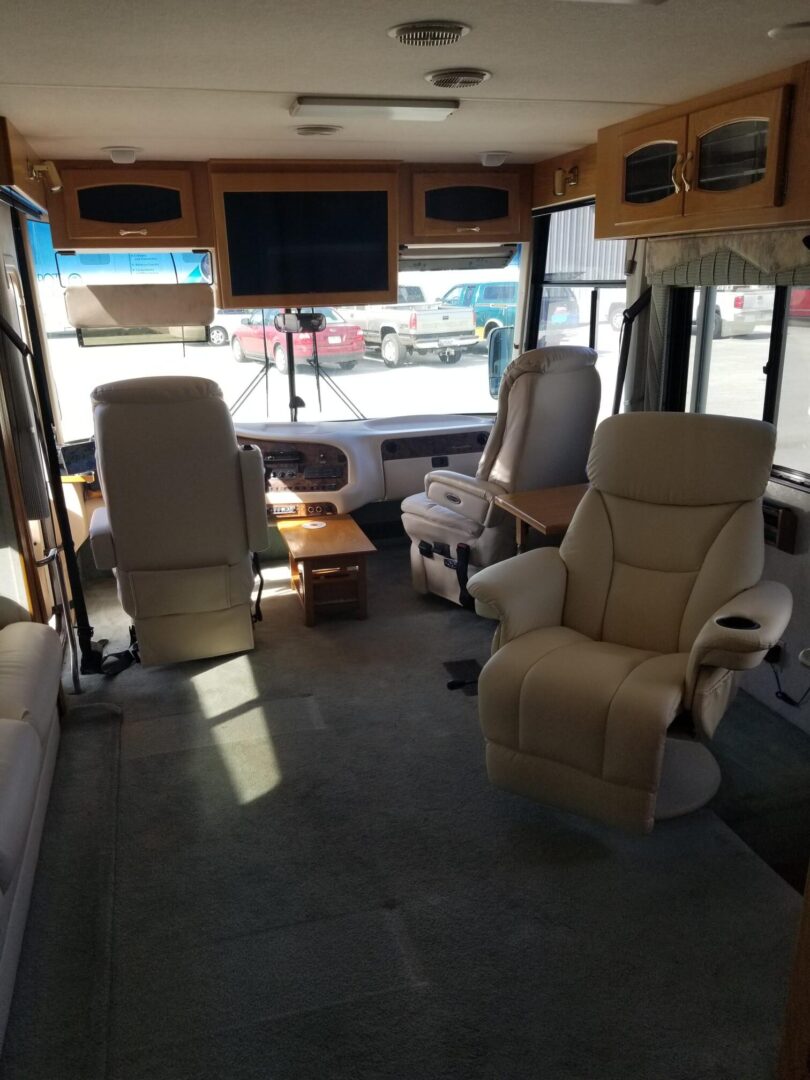An rv with a couch, chairs, and tv.