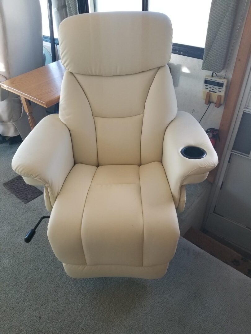 A recliner in a rv with a cup holder.