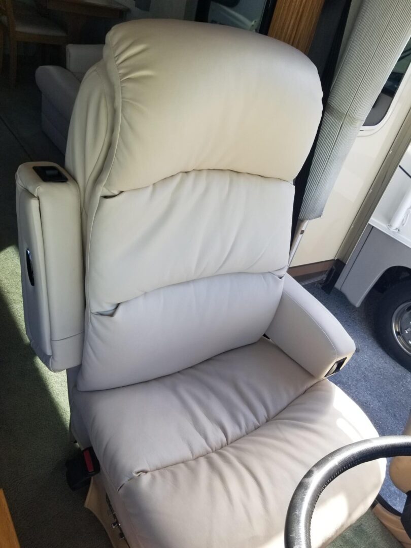 An rv seat with a white leather seat.