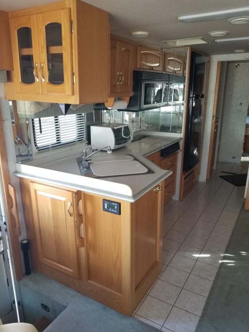A small rv with a sink, microwave, and refrigerator.