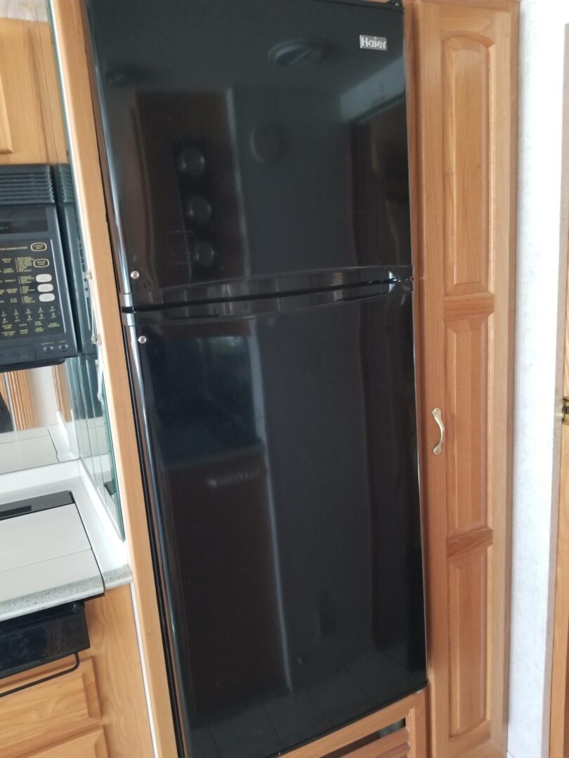 A black refrigerator in a small kitchen.