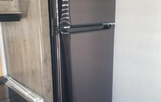 A black refrigerator is sitting in a kitchen.