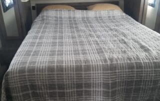 A bed in an rv with a plaid blanket on it.