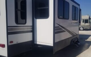 A white and black rv parked in a lot.