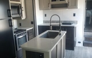 A kitchen in an rv with stainless steel appliances.