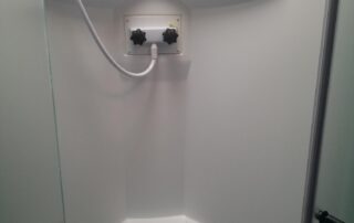 A white bathroom with a power outlet on the ceiling.