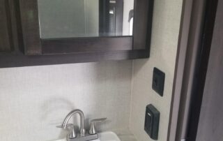 A bathroom in a small rv with a sink and toilet.