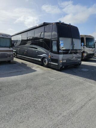 Black Prevost motorhome parked in lot.