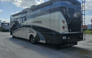 Black and beige motorhome parked outdoors.