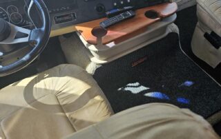 RV interior with beige seats and a wooden table.