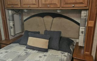 Bedroom in a motorhome with a bed and nightstand.