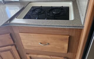 RV kitchen with two burner stovetop and drawer.